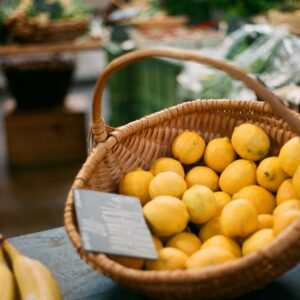 A basket of bright yellow lemons on display at a fresh produce market.